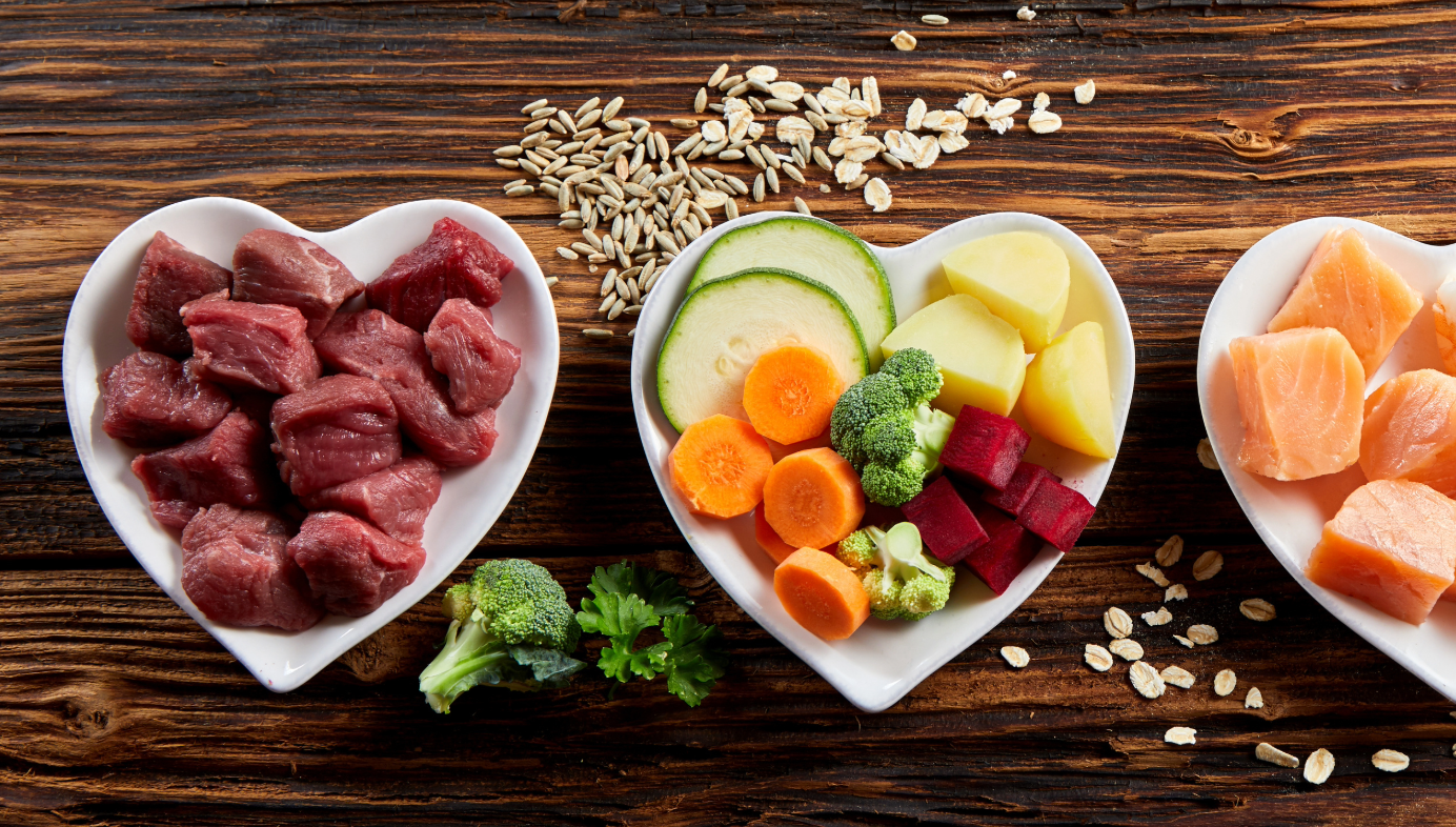 Heart-shaped plates with various food items on a wooden background